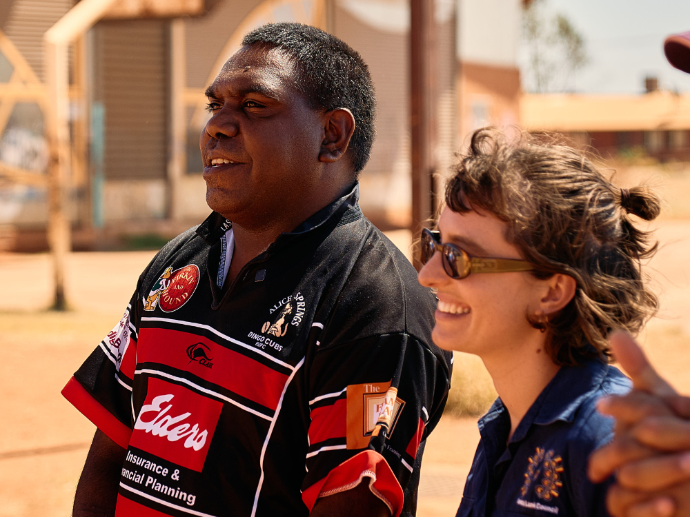 Two young people look off-camera to the left, smiling.