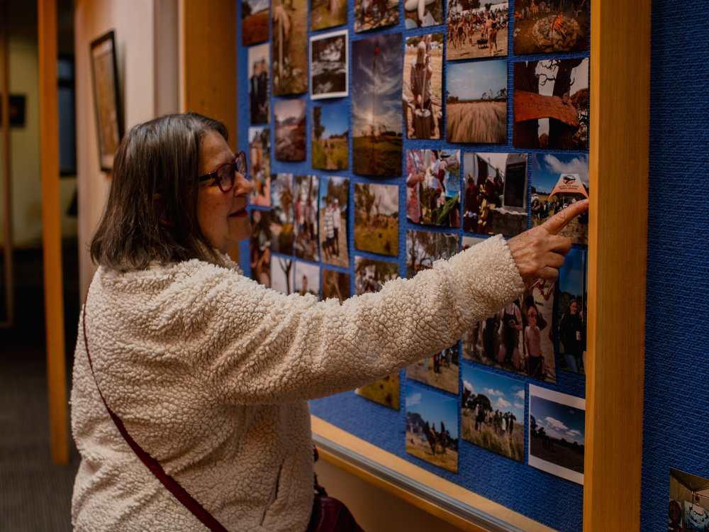 A woman points at a photo on a pinboard.
